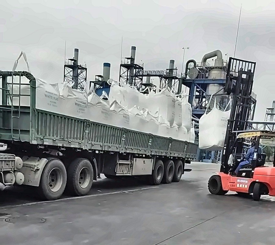 Truck loaded with jumbo bags beside a red forklift
